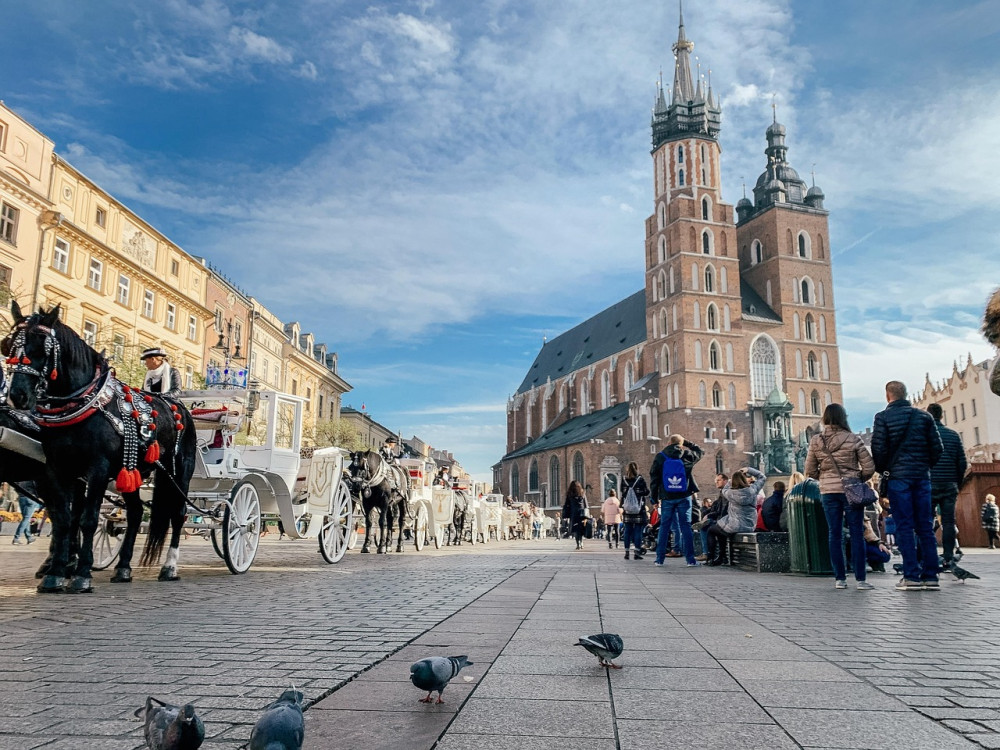 rynek w Krakowie. Widok na kościół mariacki, na płycie rynku dorożki, mieszkańcy miasta i turyści